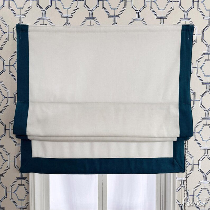 Customizable flat Roman shade in white with teal border, mounted on a window with geometric wallpaper. Ideal for light filtering or blackout.