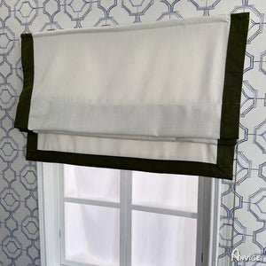 Flat Roman shade partially folded, featuring white fabric with green border. Stylish and functional window treatment for custom installation.