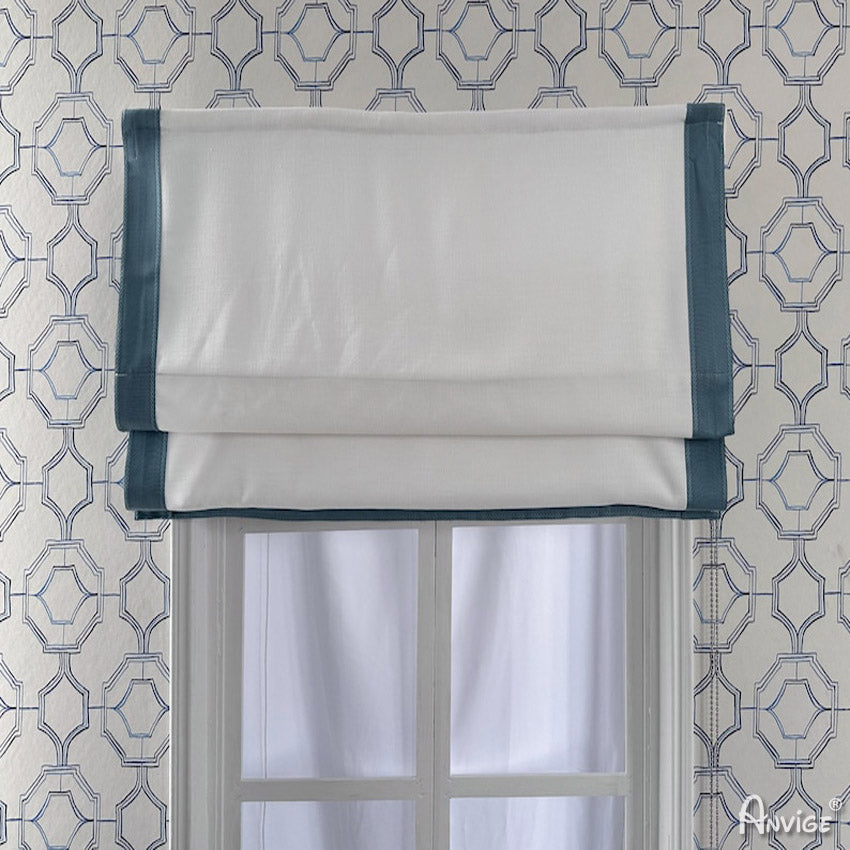 Flat Roman shade in white fabric with teal border, mounted on a window with geometric wallpaper. Customizable size and style 758 ZY.