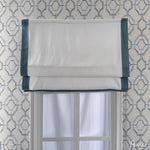 Flat Roman shade in white fabric with teal border, mounted on a window with geometric wallpaper. Customizable size and style 758 ZY.