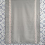 Fully extended gray Roman shade with pink decorative trim, displayed against geometric wallpaper. Customizable for any window size.