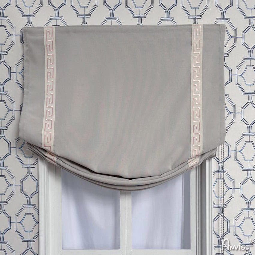 Custom gray Roman shade with decorative pink trim, mounted on a window with geometric wallpaper. Relaxed style for light control.