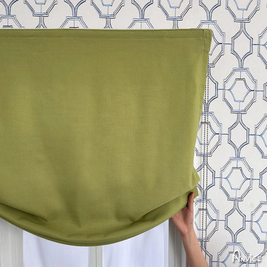 Hand adjusting green relaxed Roman shade, highlighting its soft fabric and custom fit. Anvige Style 751 ZY.