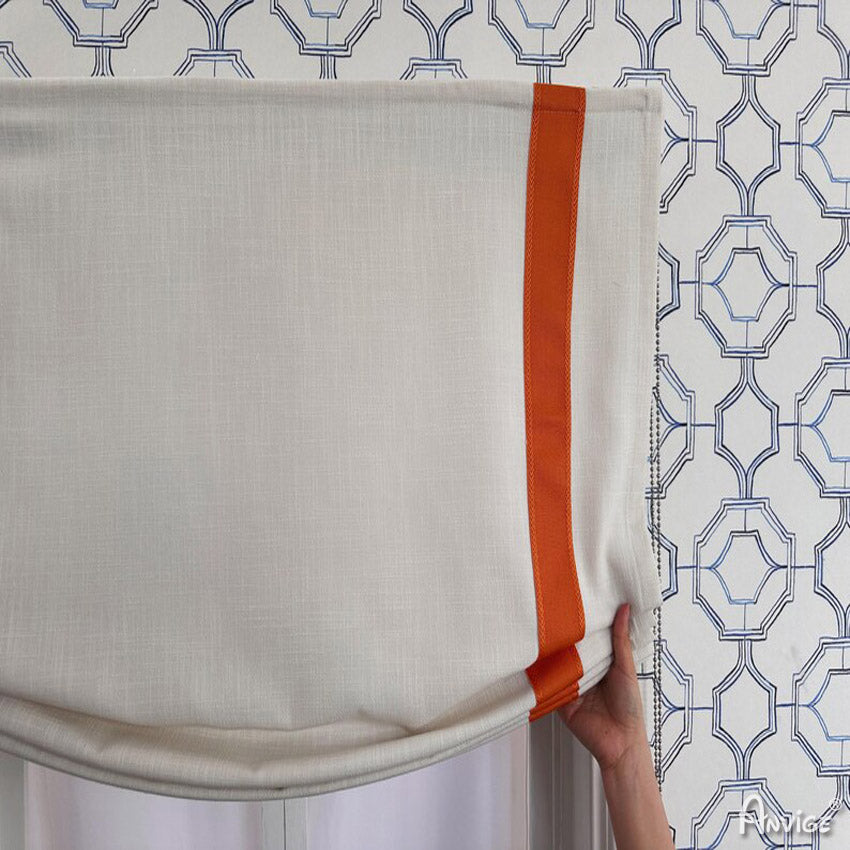 Close-up of Relax Roman Shades being adjusted, highlighting the soft white fabric and orange stripes. Designed for easy installation and customization.