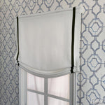 Anvige Roman Shades in white fabric with green trim, installed on a window with geometric-patterned wallpaper. Customizable and light-filtering.