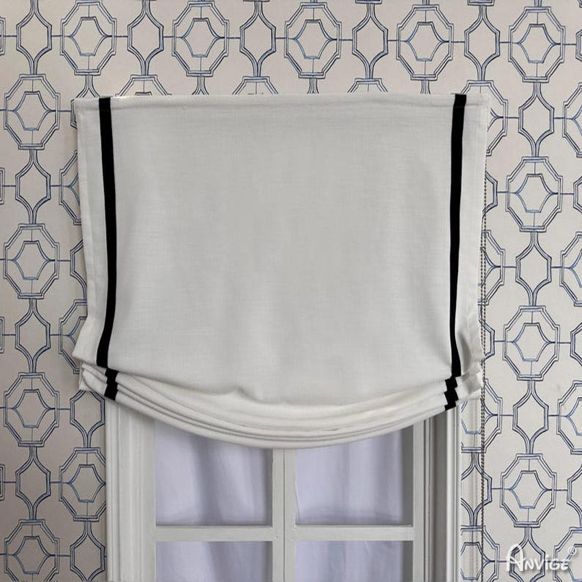 Anvige Relax Roman Shades in white with black trim, styled on a window with geometric wallpaper. Customizable for light or blackout options.