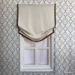 Anvige Roman Shades in beige fabric with brown trim, mounted on a window with geometric wallpaper. Customizable blackout or light filtering options.