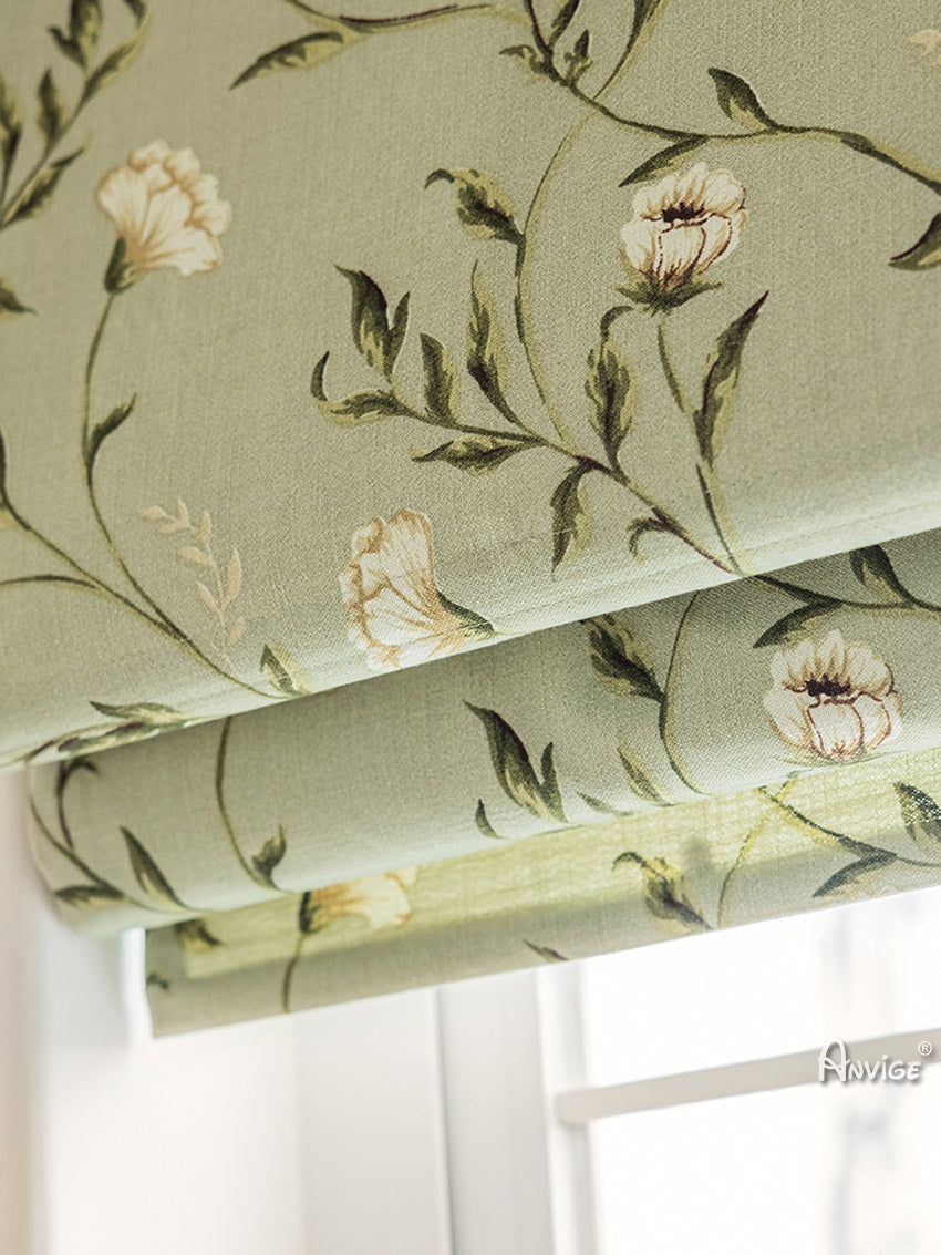 Close-up of folded Roman shade fabric with green leaves and white flowers, highlighting its elegant design and premium quality.